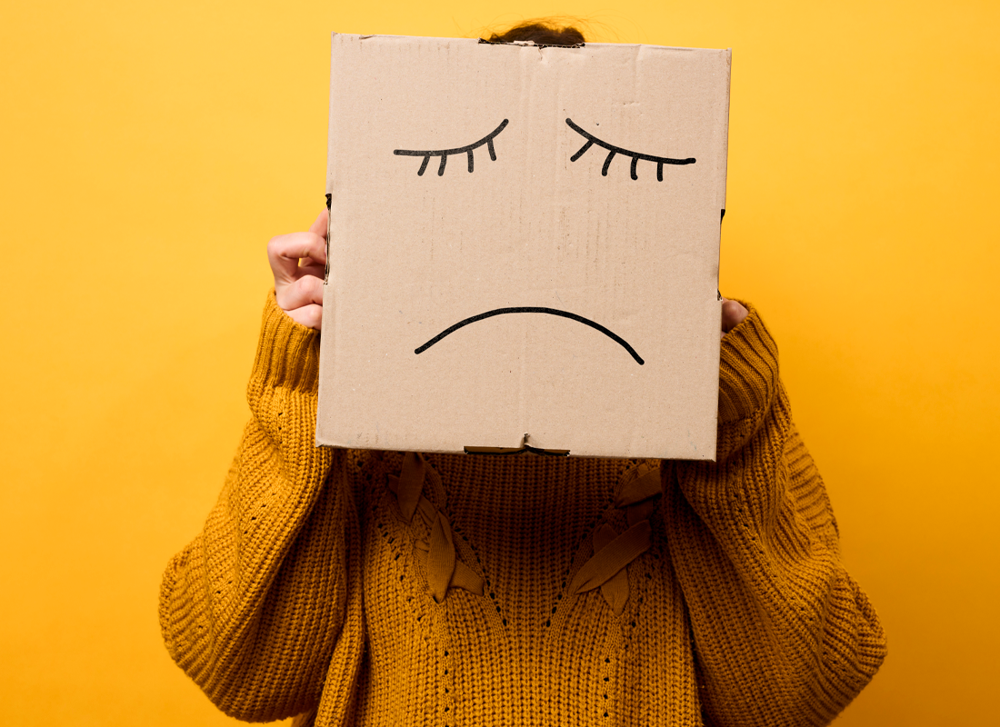 Cara triste dibujada en una caja de cartón.