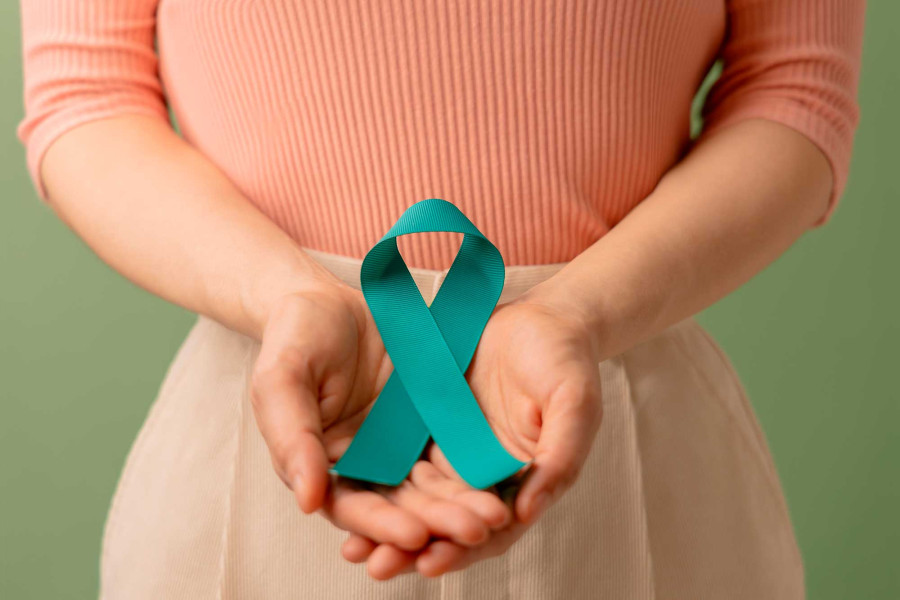 Mujer con las manos unidas manteniendo un listón verde que significa la esperanza de supervivencia ante el cáncer