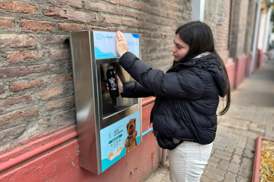 Estudiante Usach utiliza dispensador de agua que se encuentra apostado a una muralla de ladrillos 