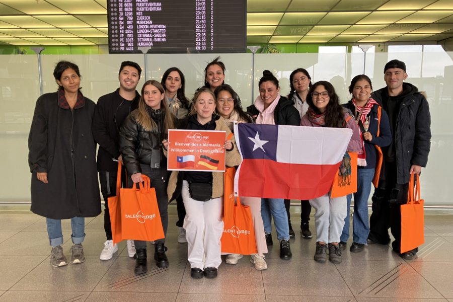 Estudiantes de Enfermería posan a al cámara en el Aeropuerto de Santiago y sostienen una bandera chilena