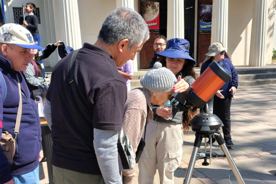 Entusiastas visitantes del AstroMuseo observan por telescopio