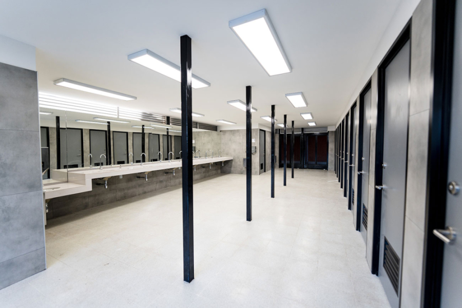 Fotografía de Baños Universales. A la derecha espejos y lavamanos. A la izquierda, puertas de los diferentes cubículos de la infraestructura.