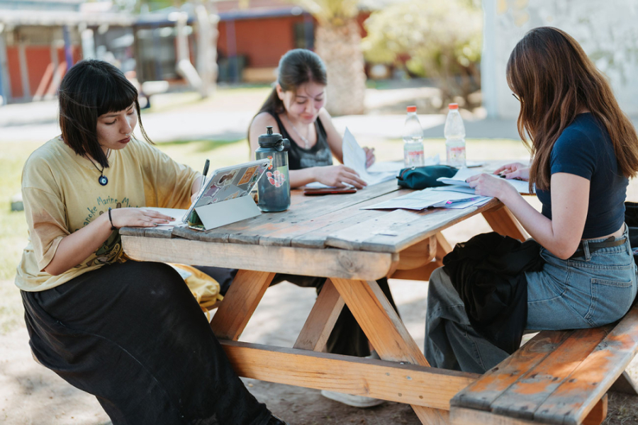 Estudiantes realizan sus tareas en un mesa de madera apostada en uno del os espacios públicos de la Universidad