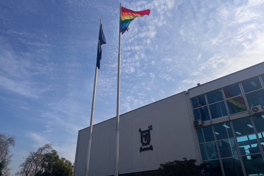 Frontis edificio de Rectoría en donde se ve flameando la bandera de la diversidad