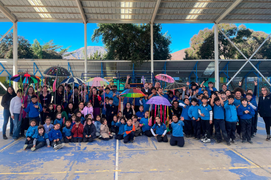Niños de una escuela de la localidad de Putaendo, posan a la cámara en la multicancha techada del establecimiento, junto a algunos profesores. Son alrededor de 50 personas y algunos estudiantes portan paraguas de colores.