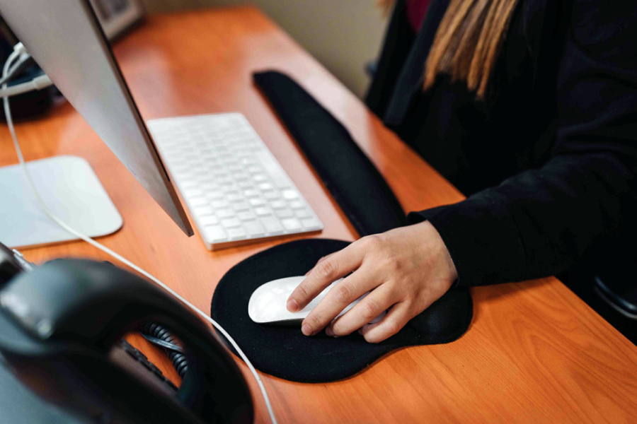 Funcionaria manipula un mouse y trabaja en su computadora.