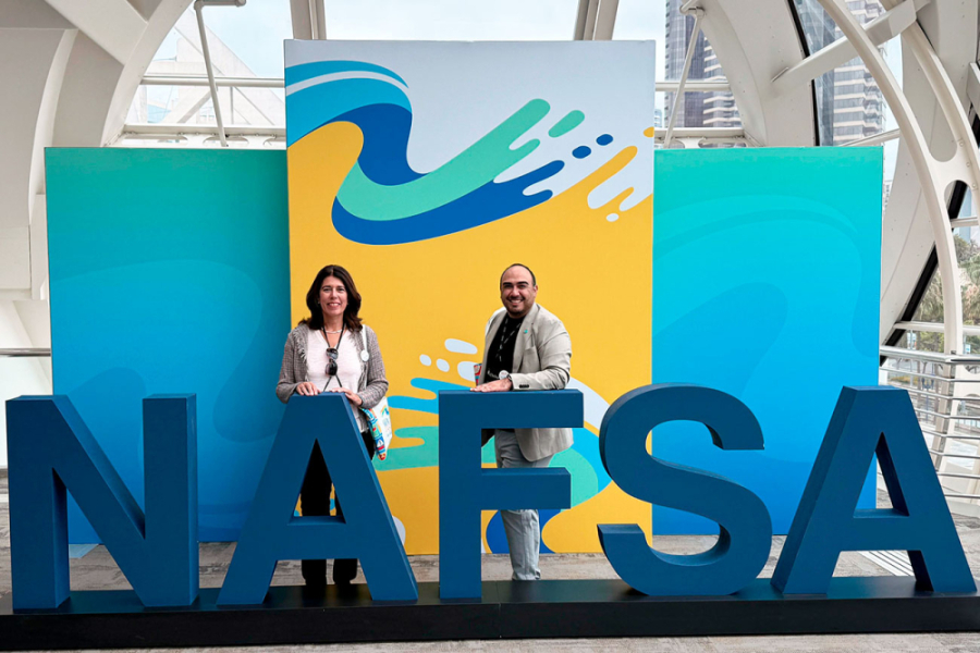 Vicerrectora de Vinculación con el Medio, Dra. Ana María Fernández y el Dr. René Garrido Lazo, posan frente a unas letras grandes que indican NAFSA, siglas de la principal feria mundial de educación internacional realizada en Estado Unidos.  