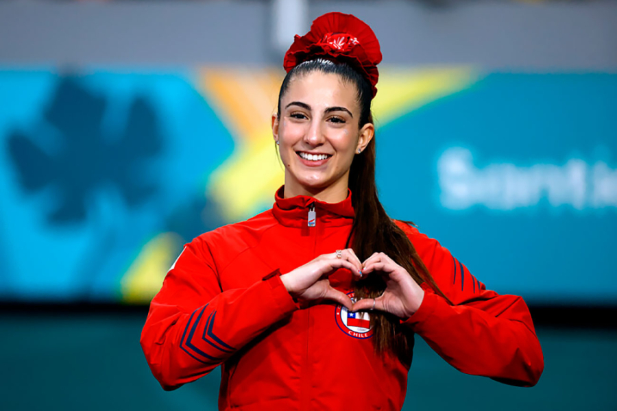 Karateca Valentina Toro, estudiante Usach. Aparece en la fotografía con buzo rojo de la selección chilena, haciendo un corazón con las manos.