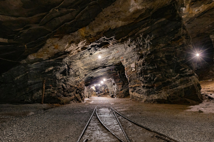 Túnel de extracción de cobre. En la imagen aparecen la roca, unos rieles y luces que iluminan la veta