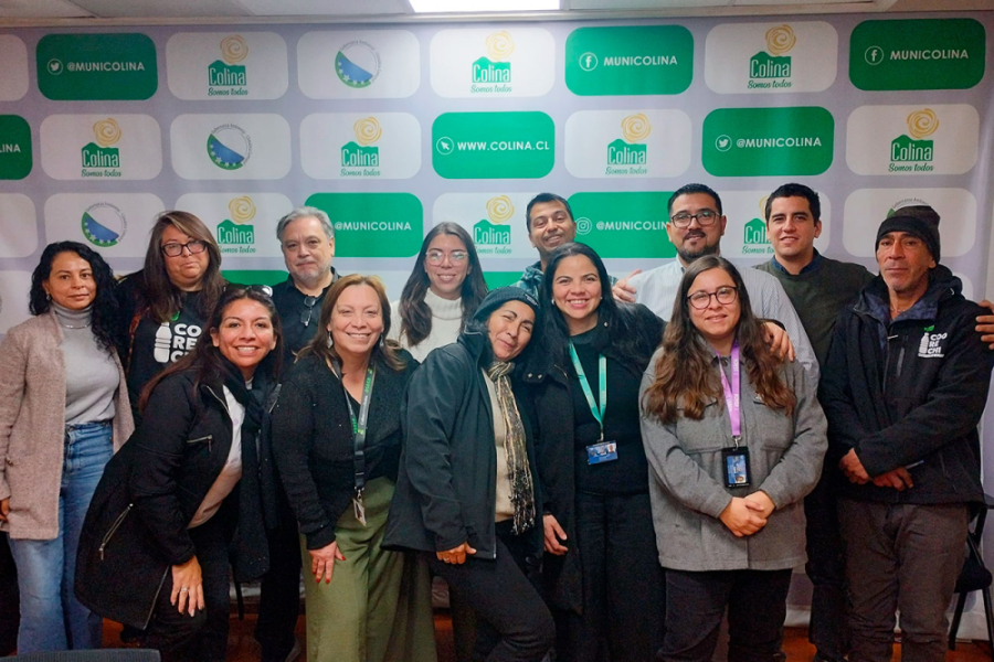 En la fotografía aparecen estudiantes del Departamento de Ingeniería Geoespacial y Ambiental junto a funcionarios de la Municipalidad de Colina. De fondo un pendón del municipio en tonos verdes y albos.