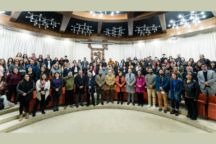 Autoridades y estudiantes posan en el Salon de Honor de la Corporación. En el fondo se aprecia el emblema de la Usach en madera.
