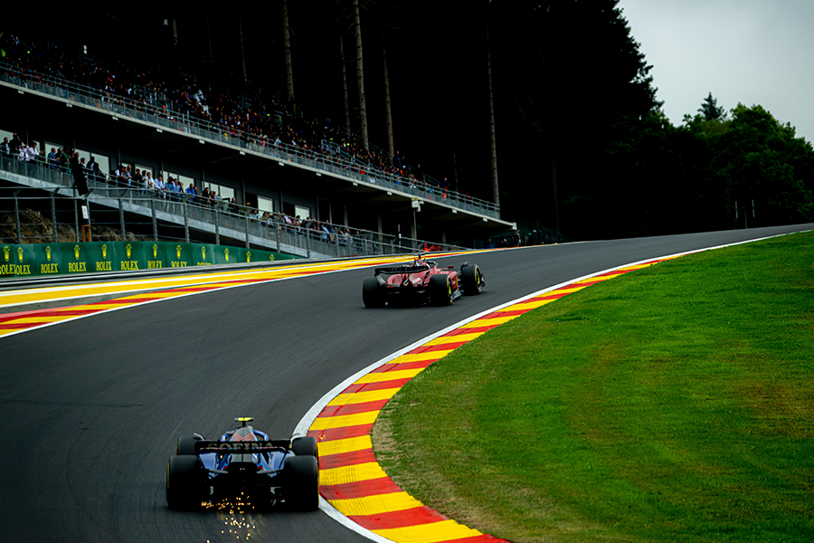 The photograph shows a race track with two cars.