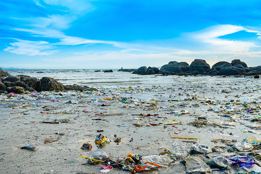 Foto de playa contaminada con botellas y residuos plásticos.