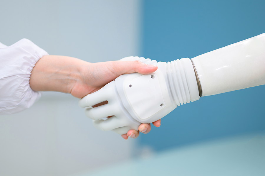 Foto de una persona y un robot dándose la mano.