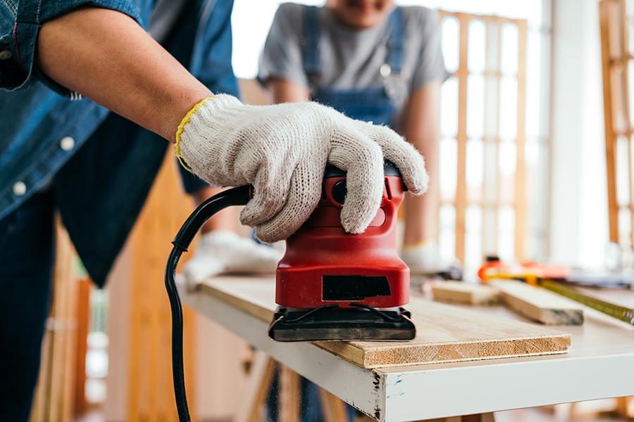 Photo of a carpentry workshop, with a hand sander in use.