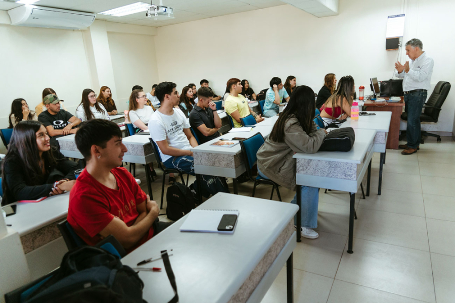 En la imagen aparece un profesor haciendo clases a un curso de la Universidad.