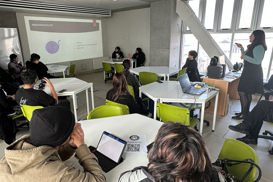 Fotografía de la actividad. Aparece en la imagen la persona que lleva adelante la charla y alrededor de ella estudiantes sentados en sus sillas y mesas
