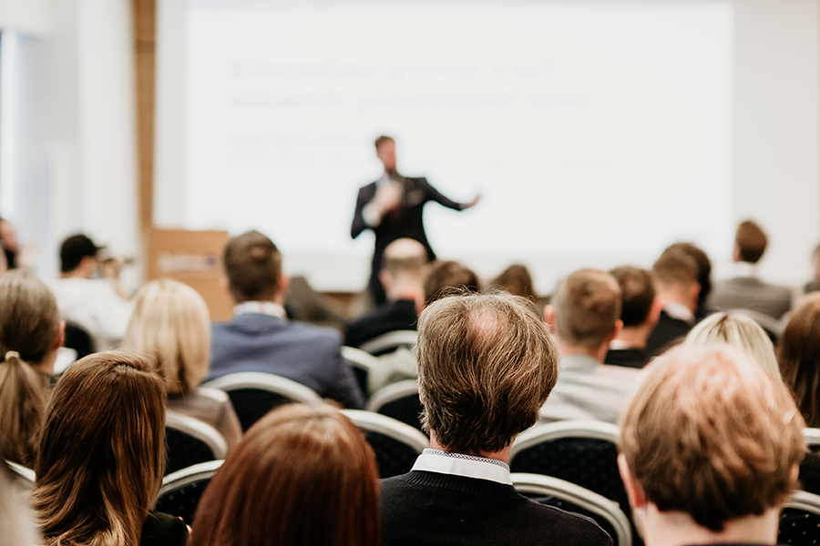 Photograph of a speaker addressing a large audience.