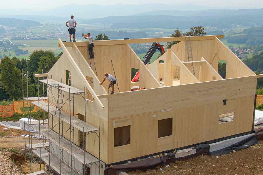 Fotografía de trabajadores de la construcción en el techo de una gran casa de madera en construcción.
