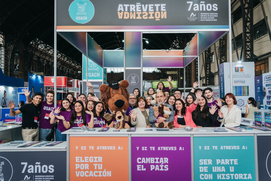 Rector Vidal, autoridades y estudiantes Usach posan en el stand de nuestra Universidad en la Feria Siad 2025. El stand tiene los colores institucionales, salmón, morado y verde esmeralda.