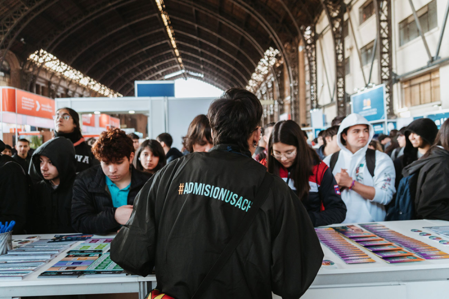 Colaborador de stand Usach atiende a estudiantes en la SIAD 2025 en la Estación Mapocho