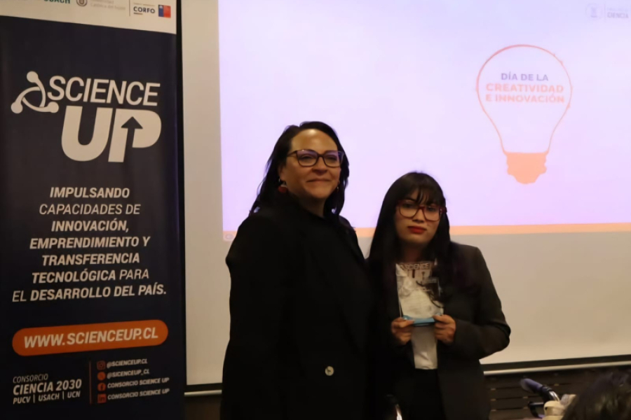 En la imagen aparecen una académica junto a estudiante. De Fondo, un pendón de Science Up