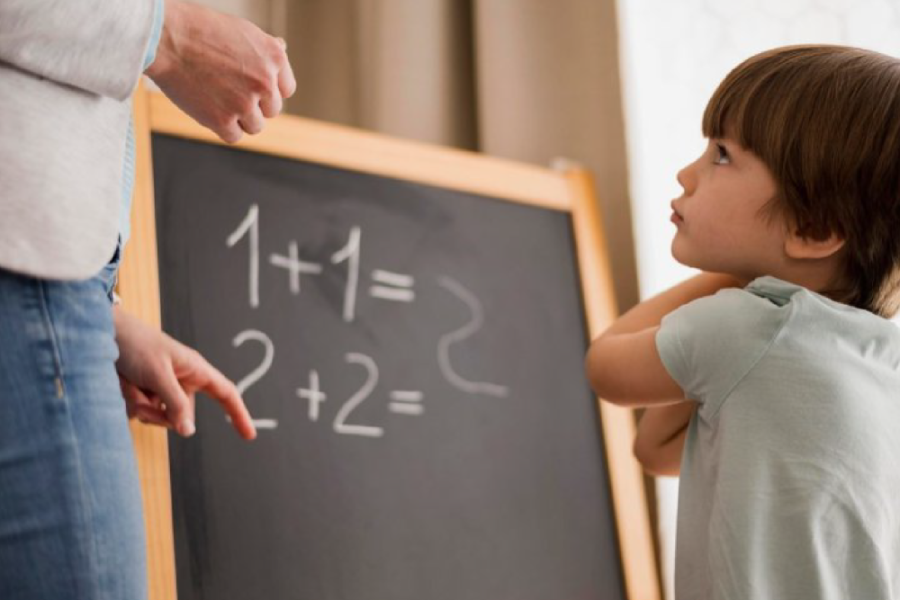 Un niño aparece frente a una pizarra y una operación matemática