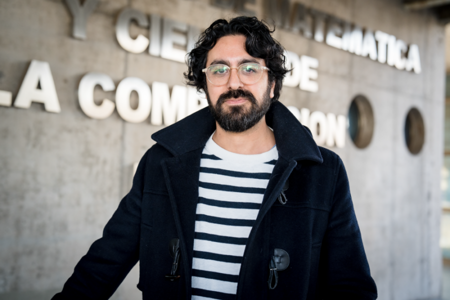 En la imagen aparece el Dr. Francisco Plaza-Vega, académico del Departamento de Matemática y Ciencia de la Computación. Viste una chaqueta negra con una polera a rayas blanco y negro- El profesor lleva puesto lentes y luce barba.