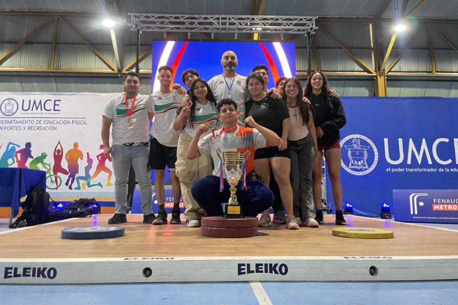 En la fotografía aparece el equipo Usach triunfador de los Juegos Nacionales Universitarios de Halterofilia, junto a su técnico y la copa. Del cuello de los deportistas cuelgan las medallas de triunfo.