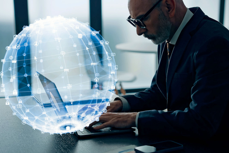 Fotografía genérica de un hombre con su computador al que lo rodea una imagen holográfica del mundo