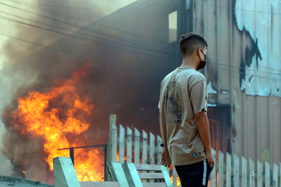 En la imagen aparece un joven mirando como se quema una casa e intentando salvar lo posible.