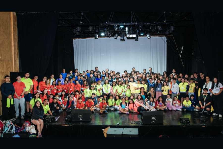 En la imagen aparecen decenas de niños en el escenario principal del Sala de las Artes Víctor Jara Usach, que participaron del Summer School 2026