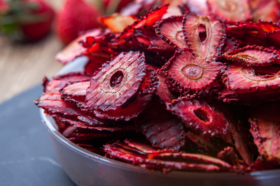Rodajas de frutilla liofilizadas de color rojo intenso en un cuenco.