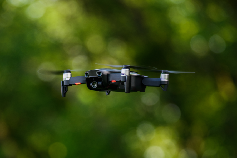 Un dron cuadricóptero sobrevolando un bosque verde.