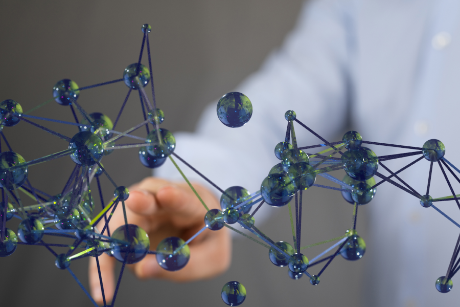 Hand reaching toward a floating 3D molecular model made of blue spheres and thin connecting lines.