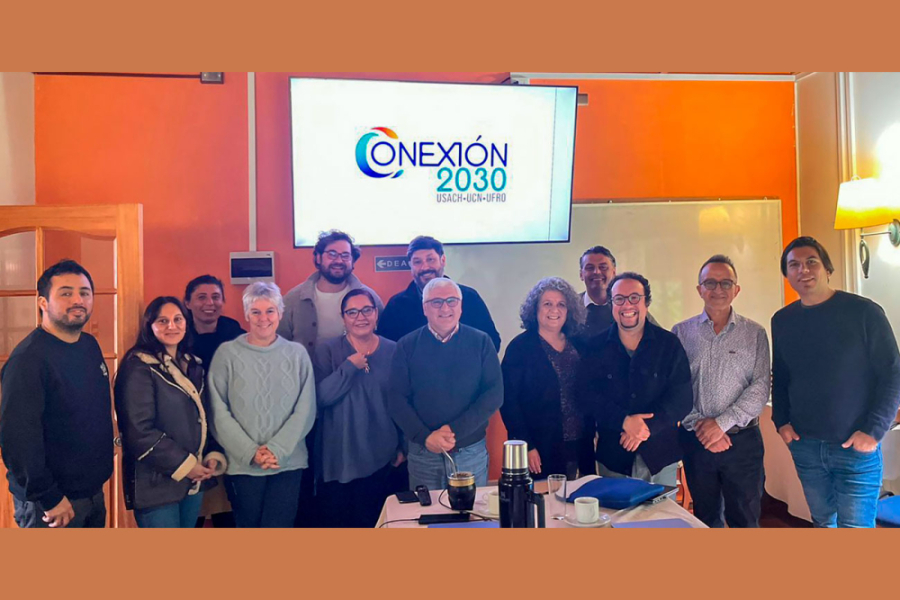 En la imagen, las y los asistentes al evento, en una sala naranja y en el fondo una pantalla que proyecta "cConexión 2030"