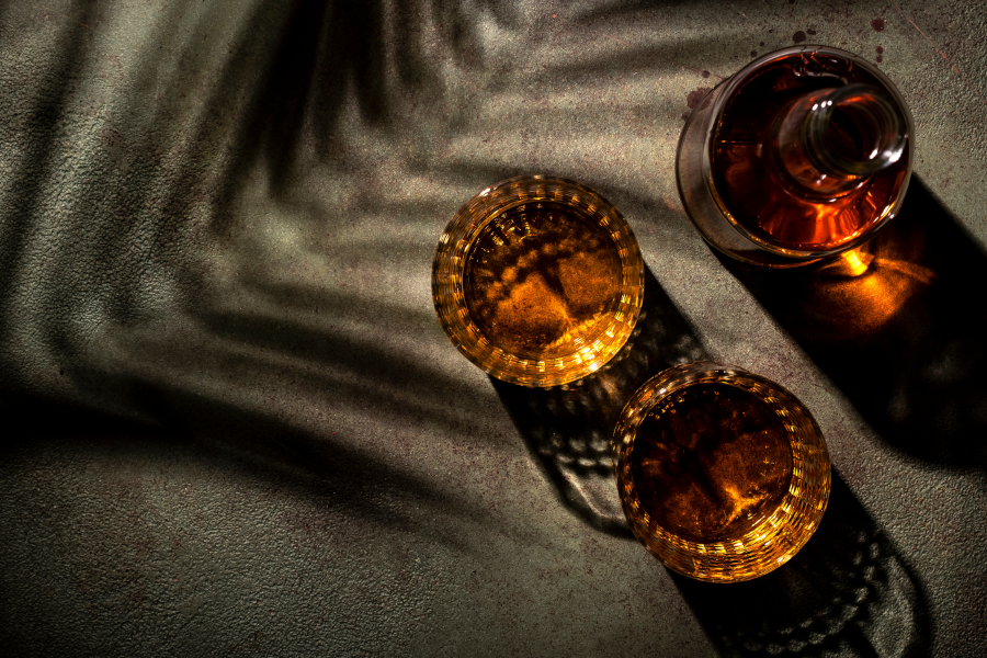 Top-down view of two whiskey glasses beside a filled bottle.
