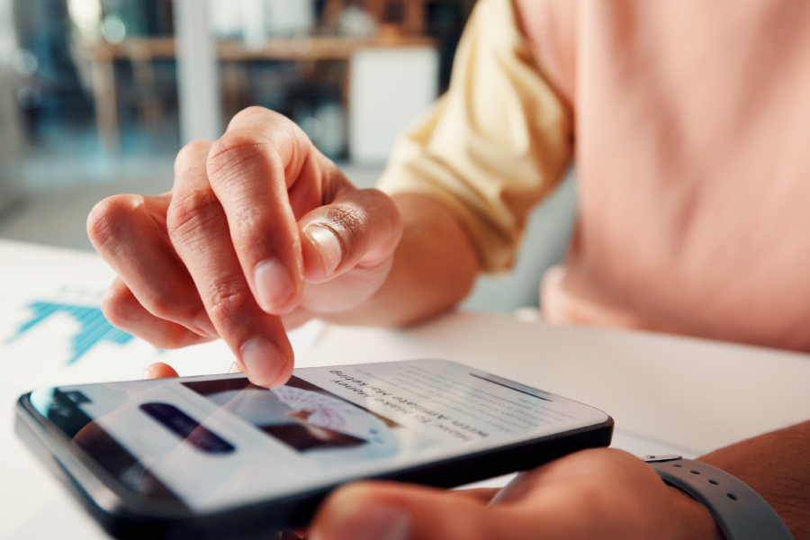 Close-up of hands using a cell phone to read an article on a desk.