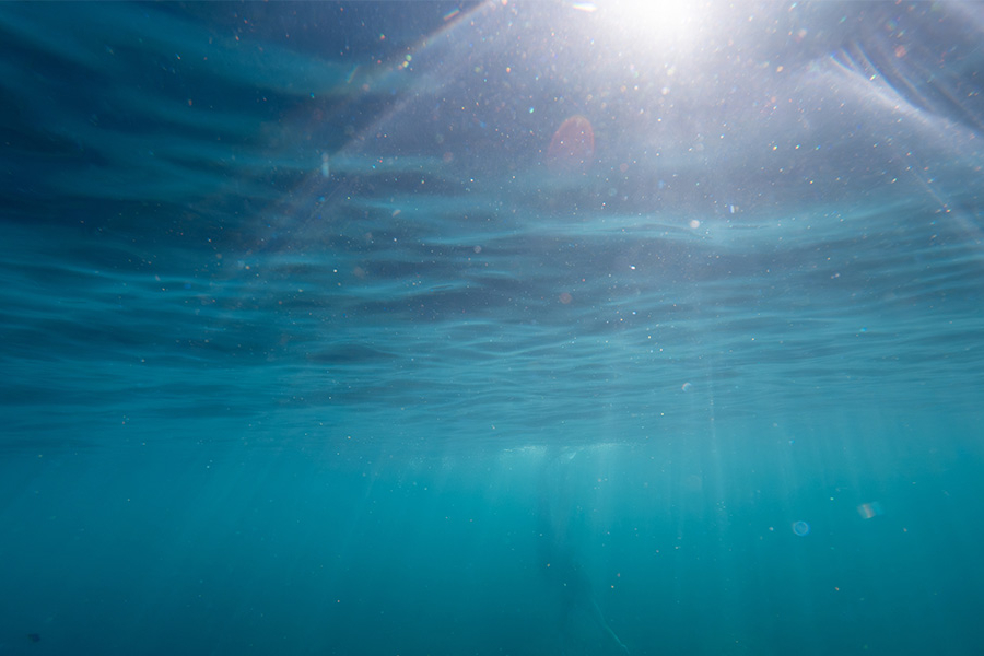 Sunlight filtering through clear blue ocean water from the surface. 