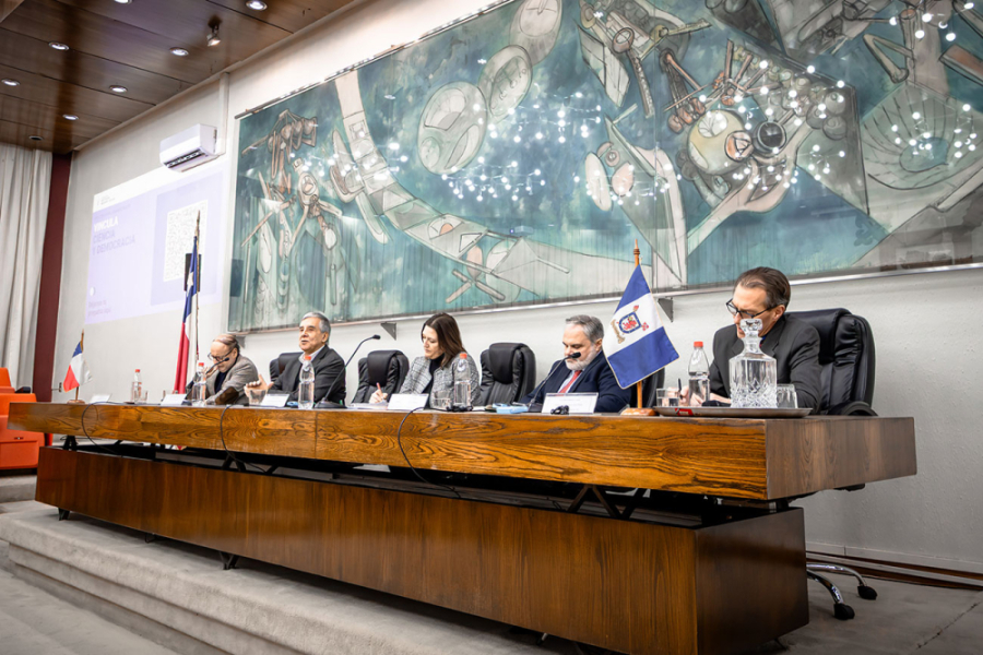 En la imagen aparecen las y los expertos que participaron del evento en la testera del Salón de Honor Usach. De fondo, el cuadro de Roberto Matta que engalana el edificio.