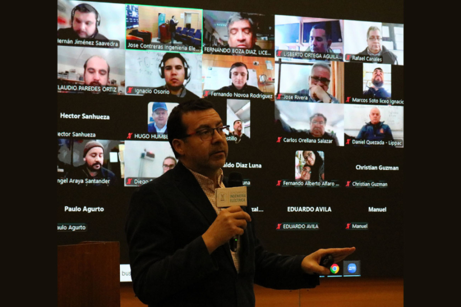 En la imagen aparece uno de los oradores de la actividad. de Fondo, una pantalla gigante con las personas conectadas vía telemática.