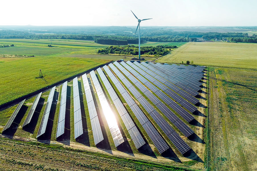 Un gran conjunto de paneles solares junto a una turbina eólica.