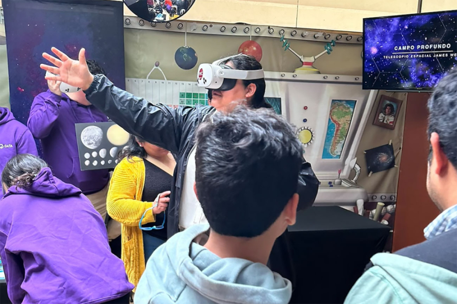 En la imagen aparece un investigador enseñando a niños y niñas que asistieron al evento. El profesor lleva puesto unos lentes de realidad virtual