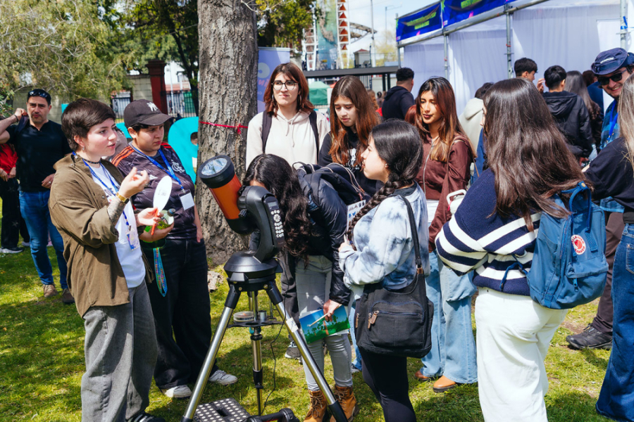 En la imagen aparecen asistentes al evento alrededor de un telescopio. 