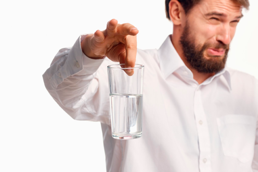 Hombre con vaso de agua y cara de asco